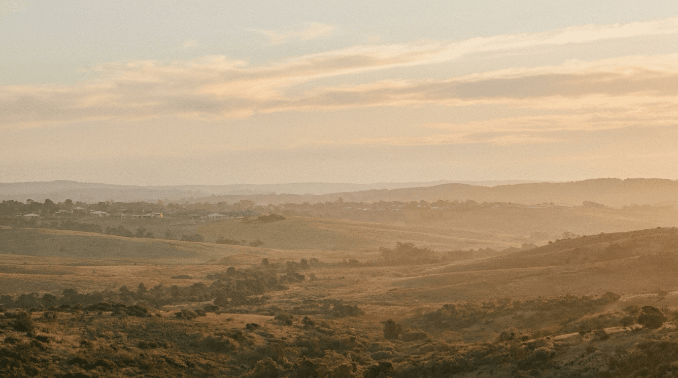 Regional Australian valley at golden hour with distant suburban dwellings on the horizon — editorial composition for a piece on the 1 July 2027 CGT apportionment formula