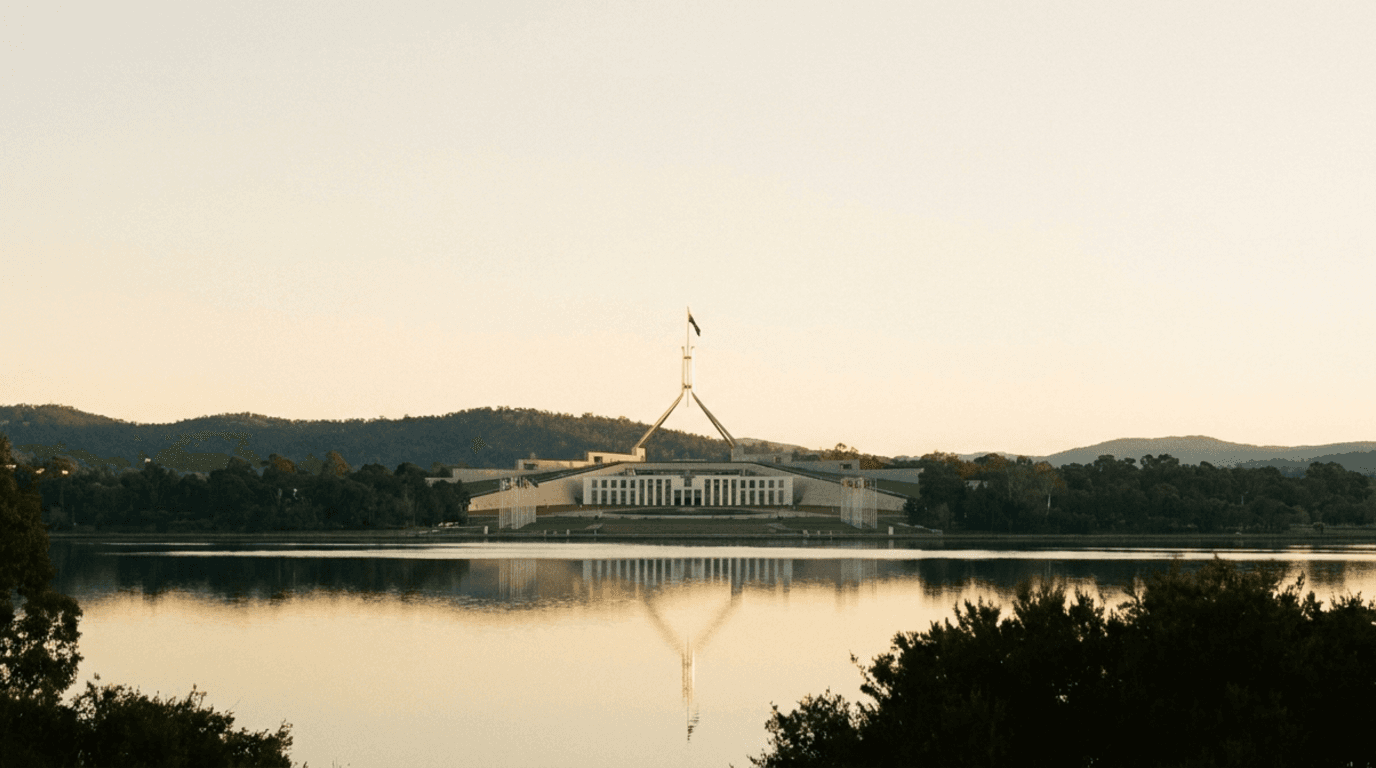 Australian Parliament House in Canberra at dawn, reflected in Lake Burley Griffin — the seat of the 2026 tax reform legislation